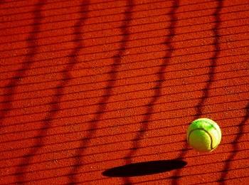 Tennis ball about to land on a clay tennis court