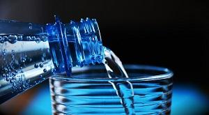 Bottle of water pouring into a a glass